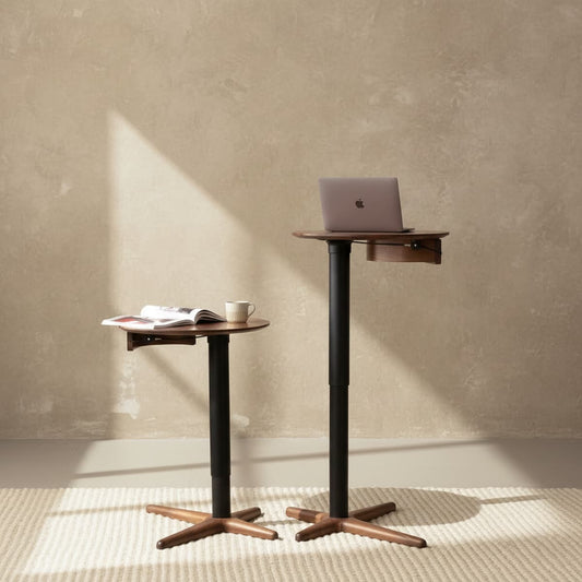 Adjustable height standing desks with solid black walnut tops and bases, one with laptop, one with book and mug