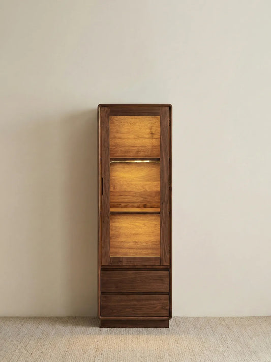 Alt Text:Full front view of the Walnutry Kurumi series narrow display cabinet in warm ambient light.