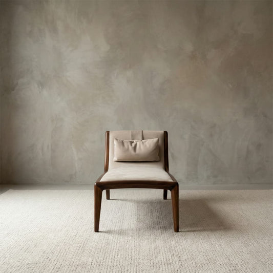 Contemporary armless accent chair with cream upholstery and a lumbar pillow, supported by a sleek solid walnut wood structure.