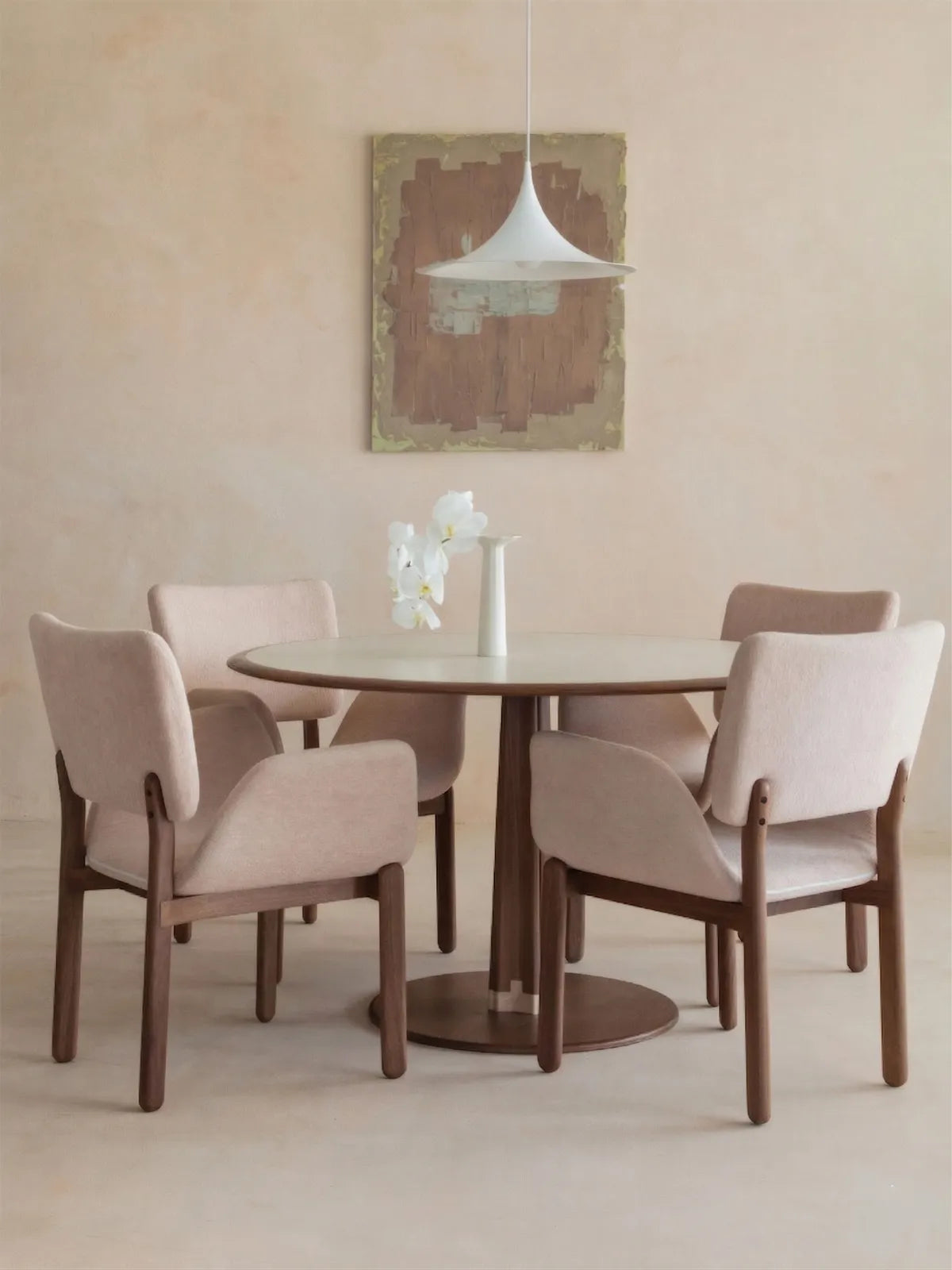 Set of four beige upholstered walnut dining armchairs around a round pedestal dining table