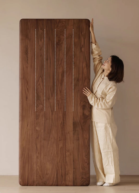 Woman in beige outfit standing beside large solid North American Black Walnut wood panel with natural grain
