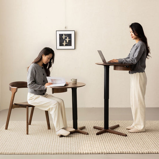 Adjustable height walnut side table shown in sitting and standing positions with woman reading and using laptop