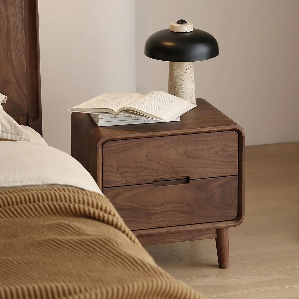 Solid walnut nightstand with two drawers, black and beige modern table lamp, open book on top, cozy bedroom setup