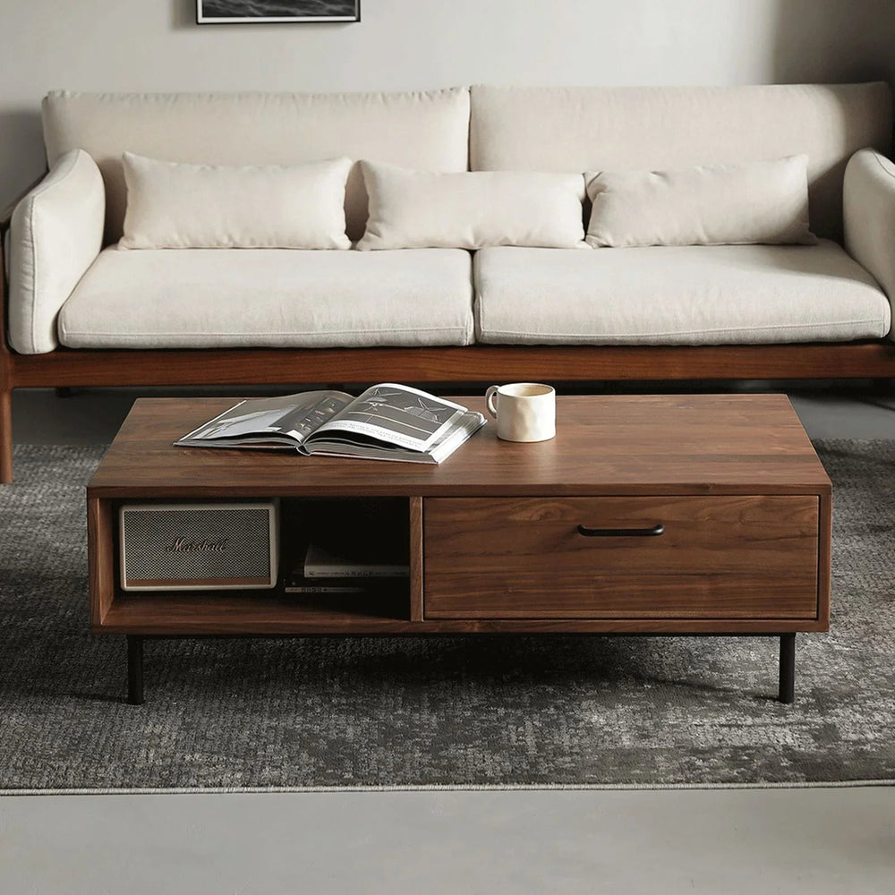 Modern living room with solid walnut coffee table featuring drawers, open shelf, book, and mug on gray rug