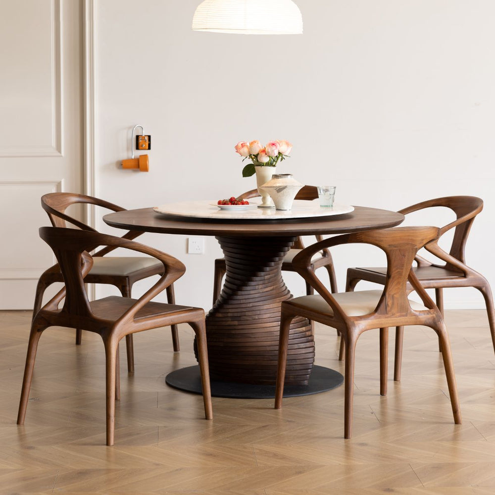 Mid-century modern solid black walnut dining table with sculptural base and four matching armchairs in a bright room
