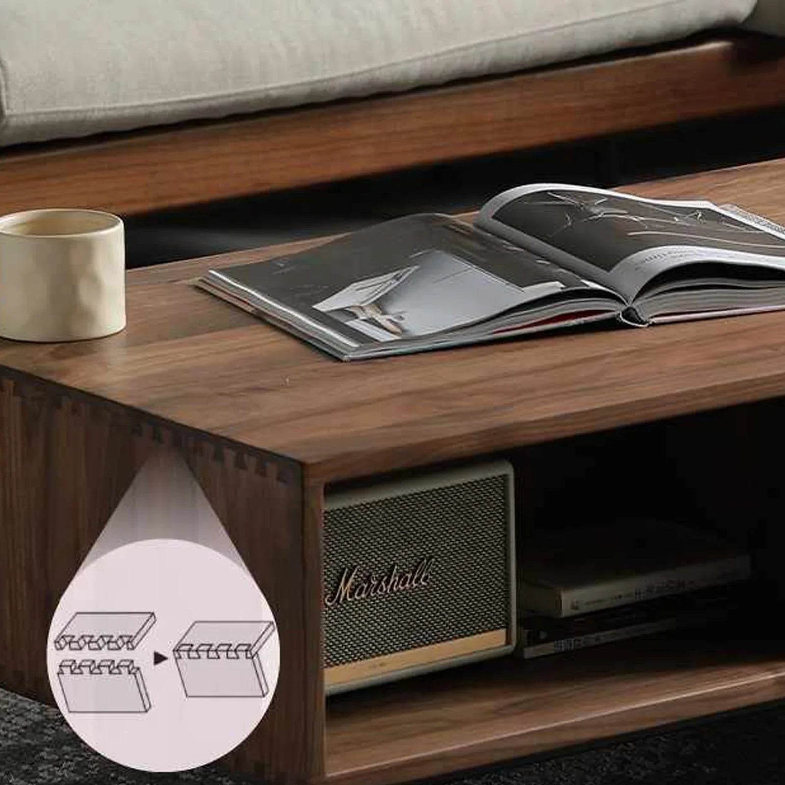 Close-up of 100% solid walnut drawer box corner showing dovetail joint with open magazine and speaker on walnut coffee table