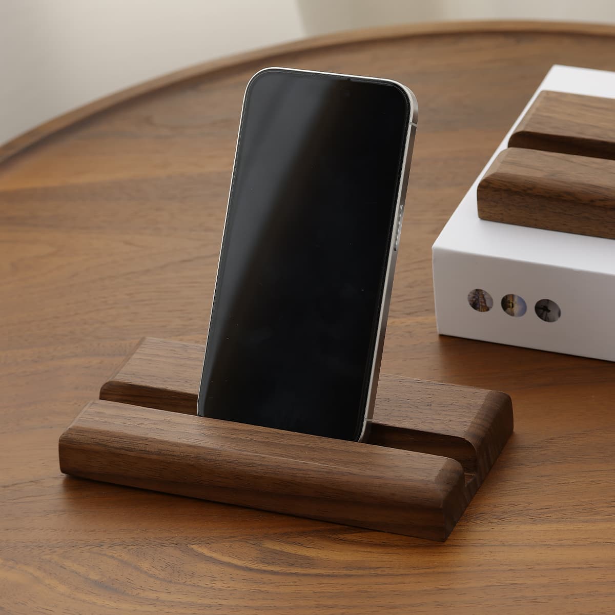 Modern smartphone standing in a solid North American black walnut wooden holder on a walnut table