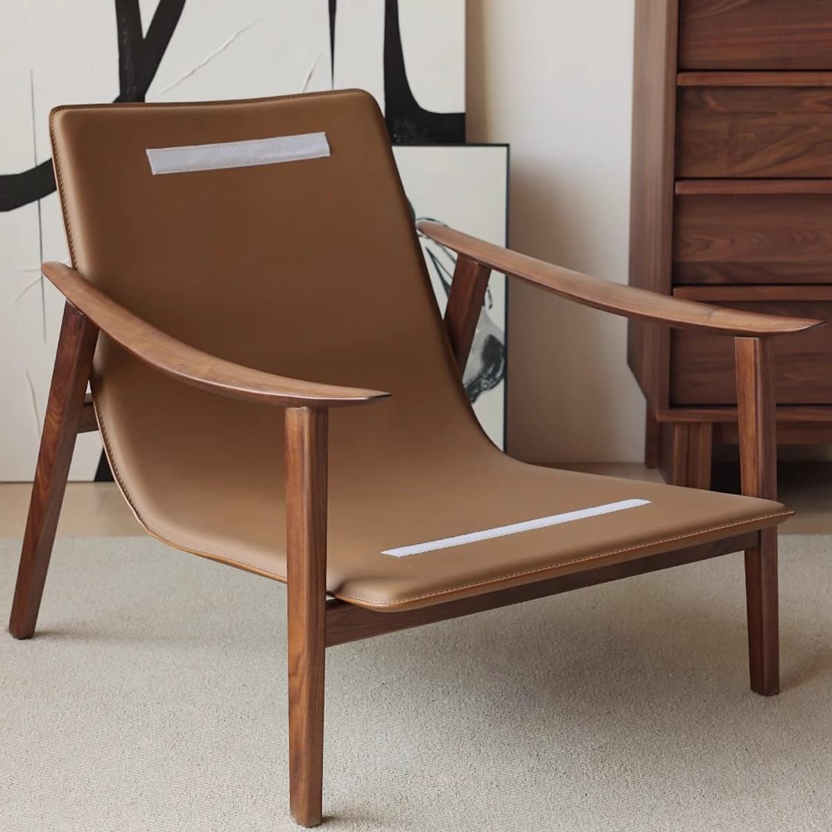Mid-century modern lounge chair with tan leather seat and solid North American black walnut frame on beige carpet
