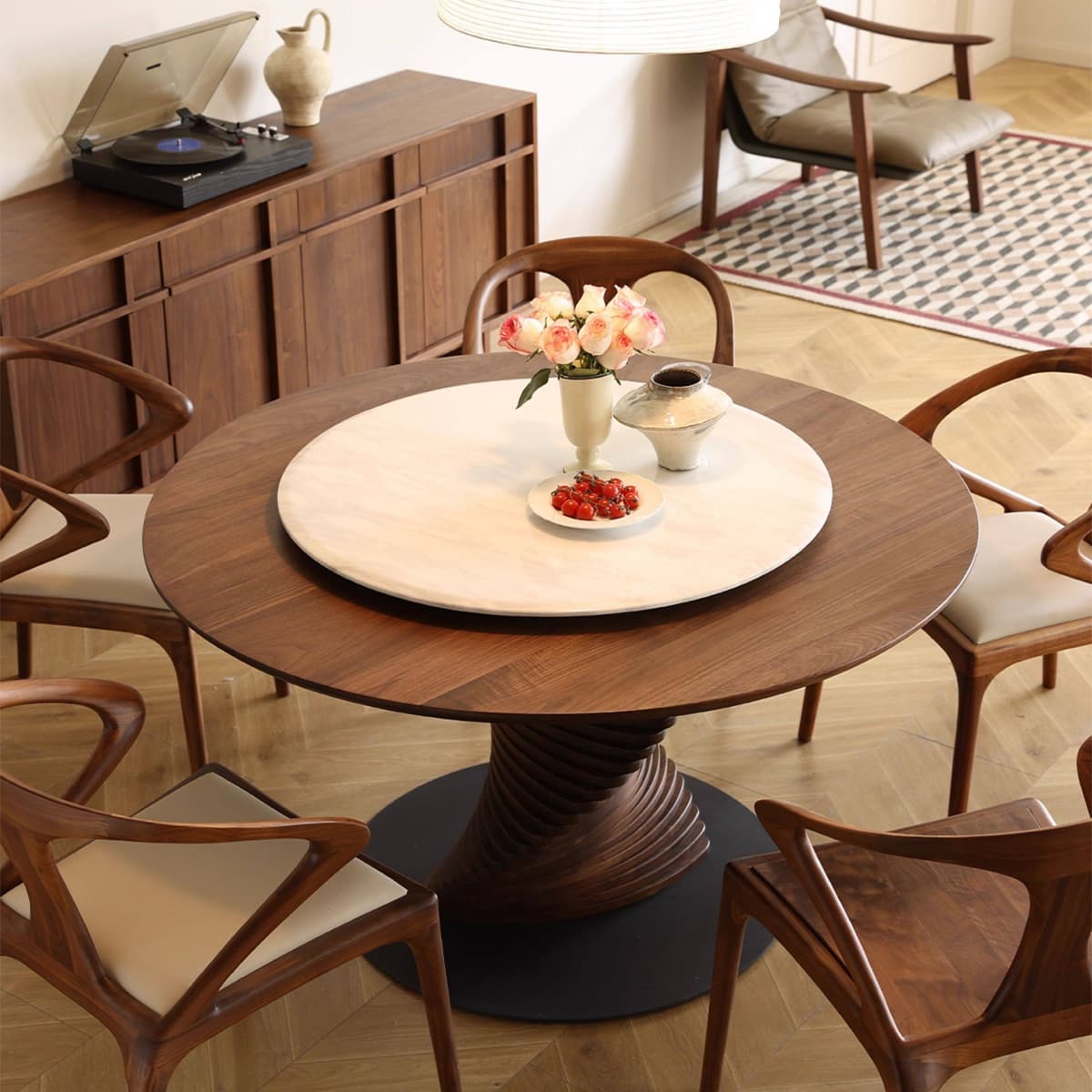 Round wooden dining table with marble center, surrounded by six walnut chairs, in a modern living room