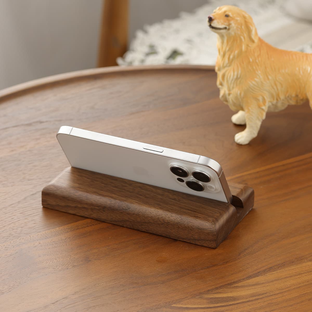 White smartphone resting on handcrafted solid black walnut wooden stand on walnut furniture table