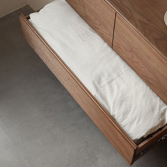 Open wooden drawer with textured front panel holding folded white linen on a concrete floor