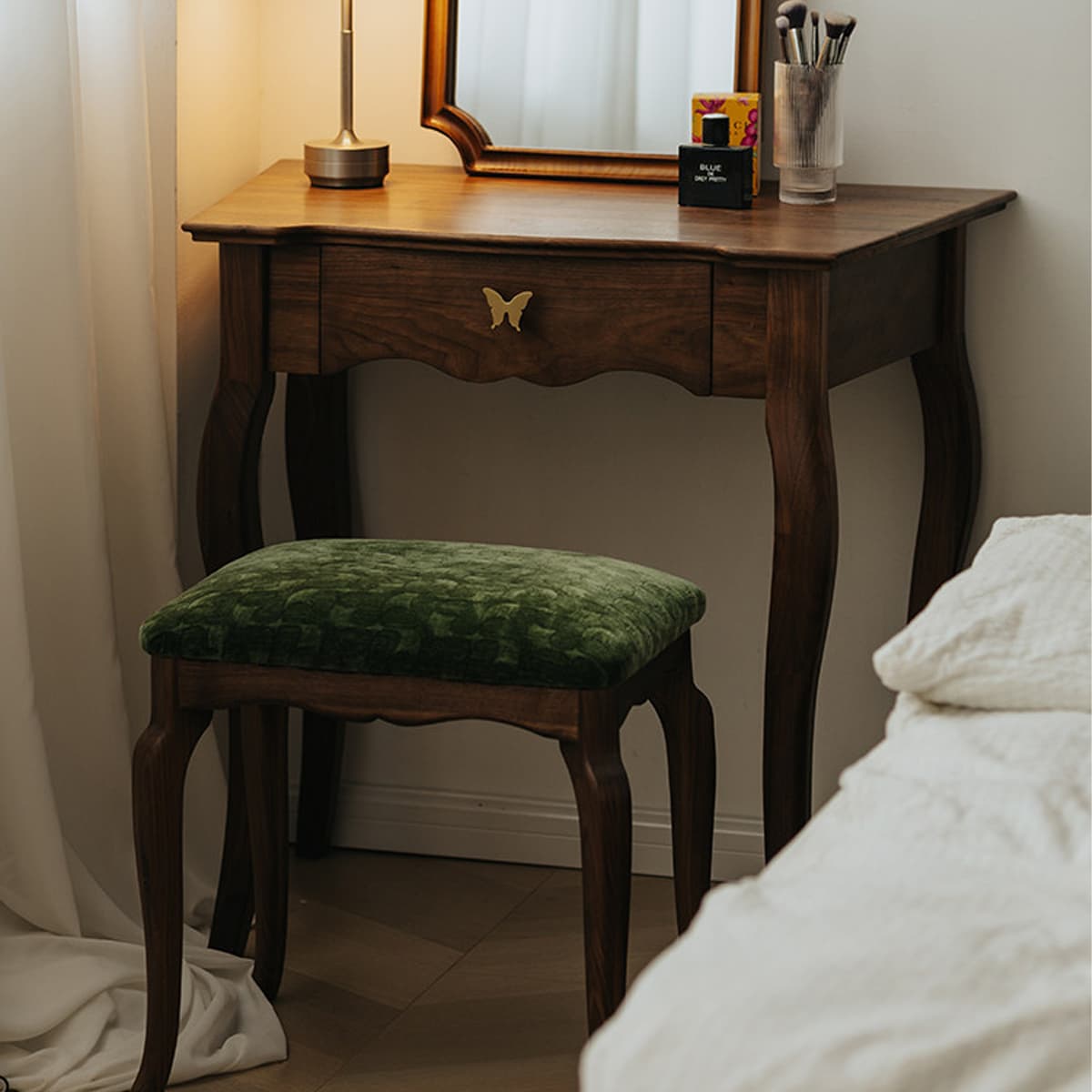 Solid black walnut dressing table with butterfly drawer handle and green velvet cushioned stool in cozy bedroom