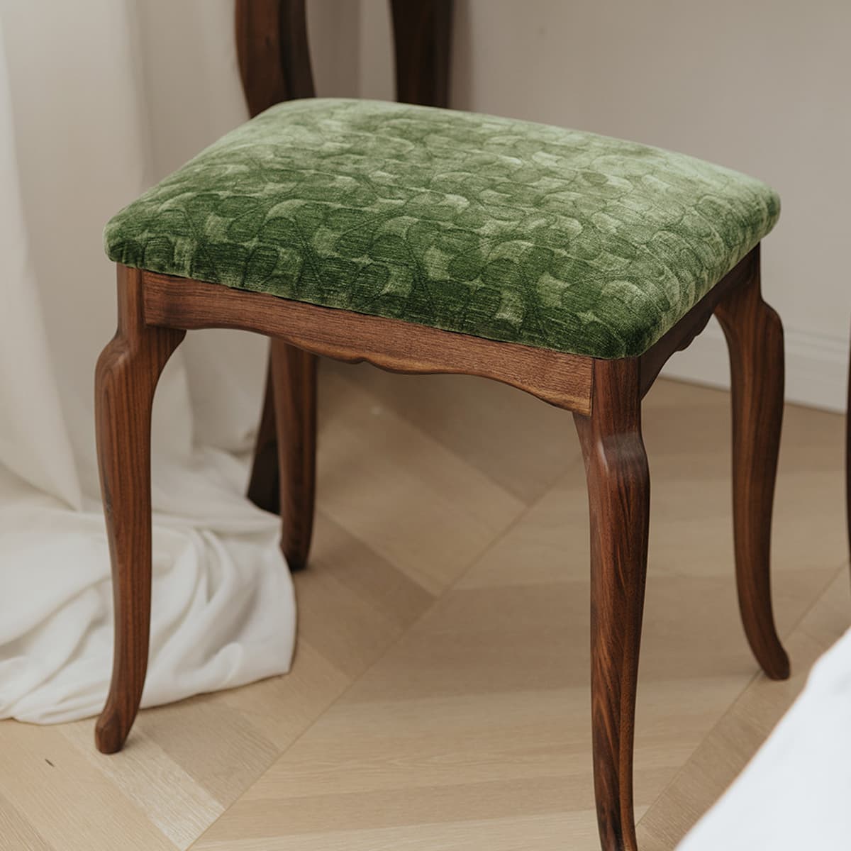 Heirloom-quality stool with carved solid black walnut legs and green textured upholstered cushion