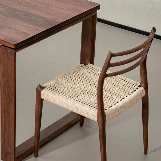 Solid North American black walnut dining table with handcrafted woven seat chair on light tile floor