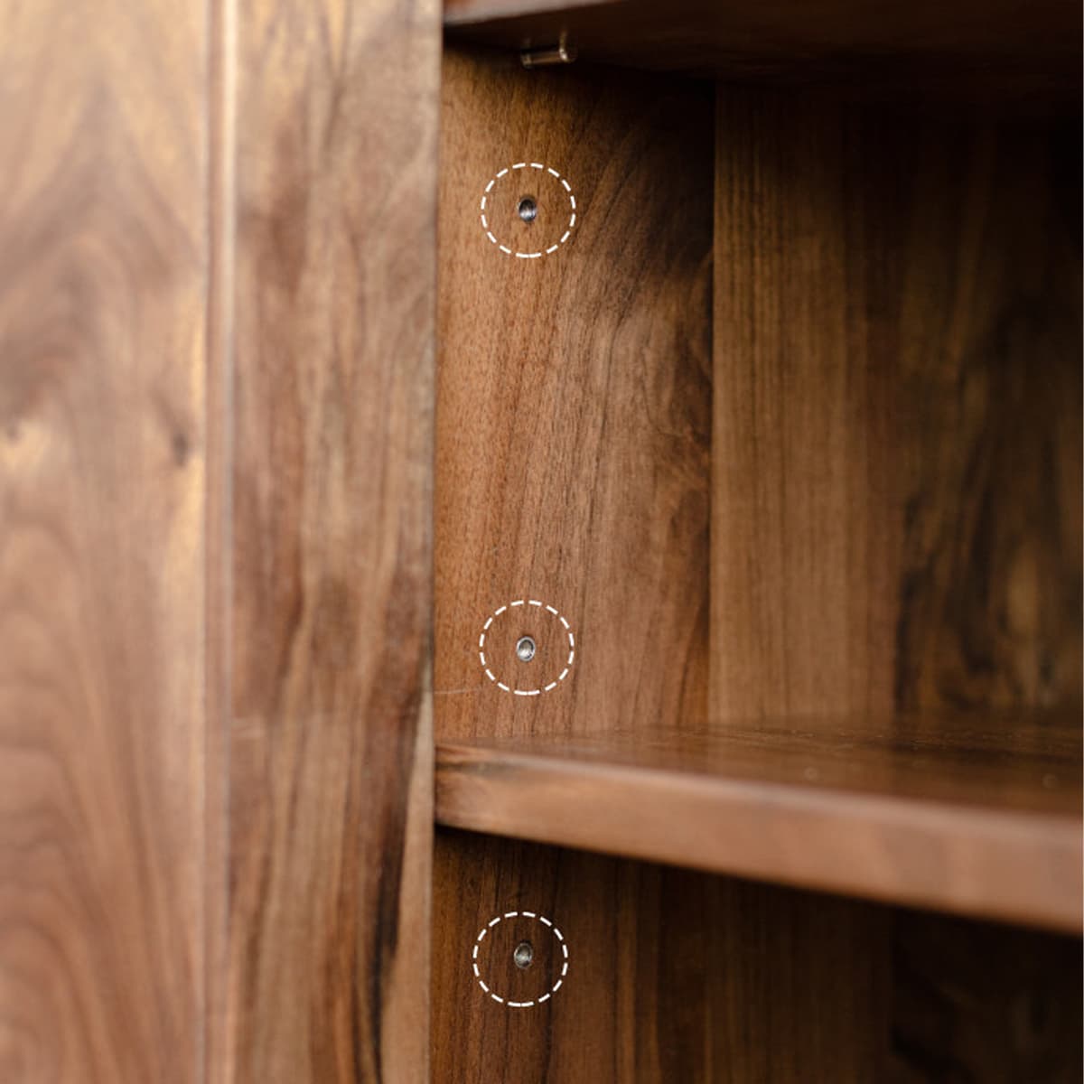 Close-up of solid black walnut wood bookshelf interior showing adjustable shelf holes with natural oil finish