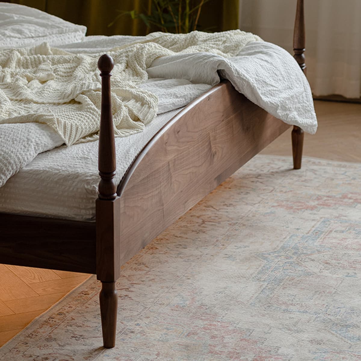 Heirloom-quality solid black walnut bed with turned posts, white bedding, and a knit cream blanket on a vintage patterned rug