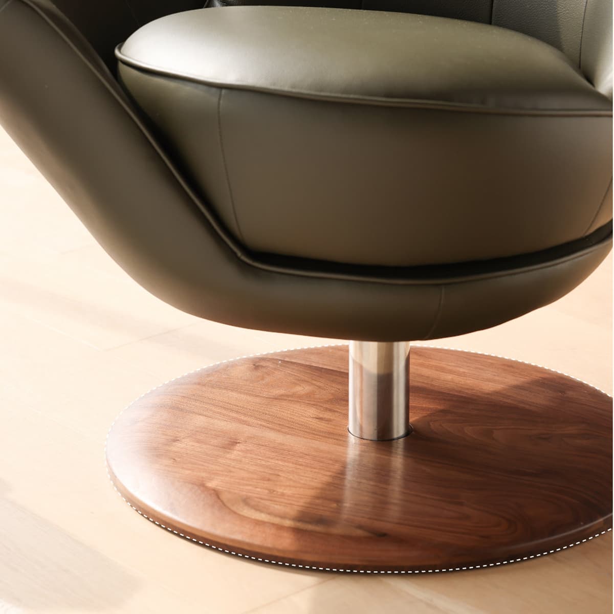 Close-up of modern swivel chair with black leather seat and solid North American black walnut circular base