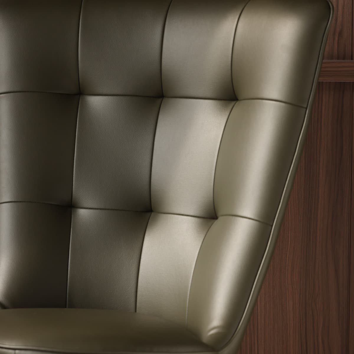 Close-up of tufted olive green leather chair with black walnut wood panel background