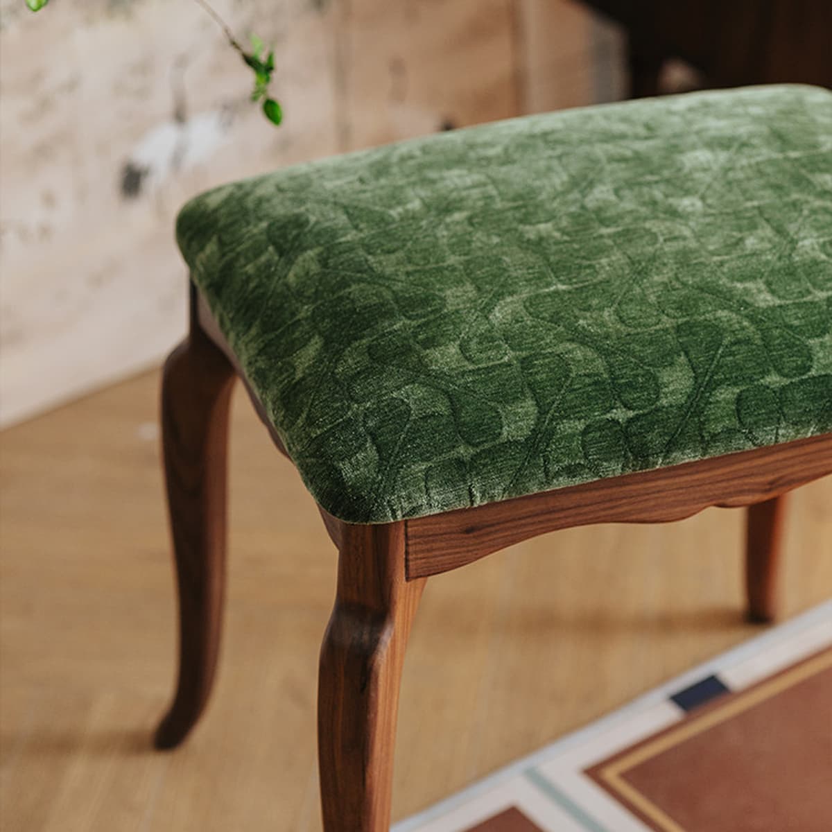 Close-up of solid North American Black Walnut stool with plush green patterned upholstery