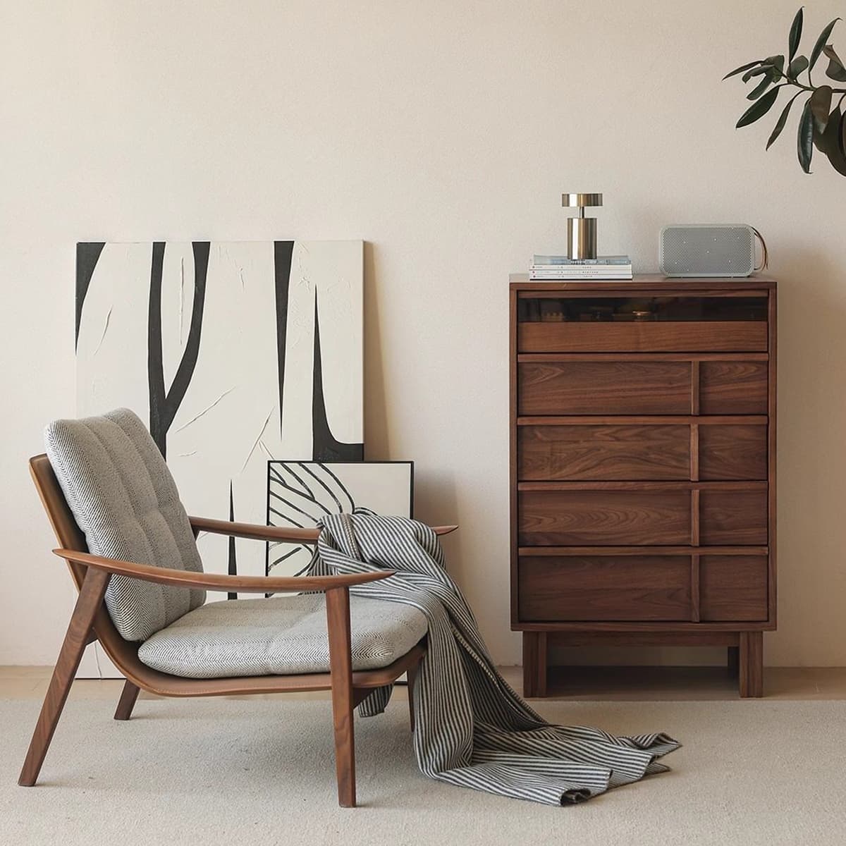 Mid-century modern solid black walnut dresser with gray cushioned armchair and striped throw in minimalist room