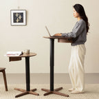 Woman using adjustable height walnut side table as standing desk in minimalist room with artwork