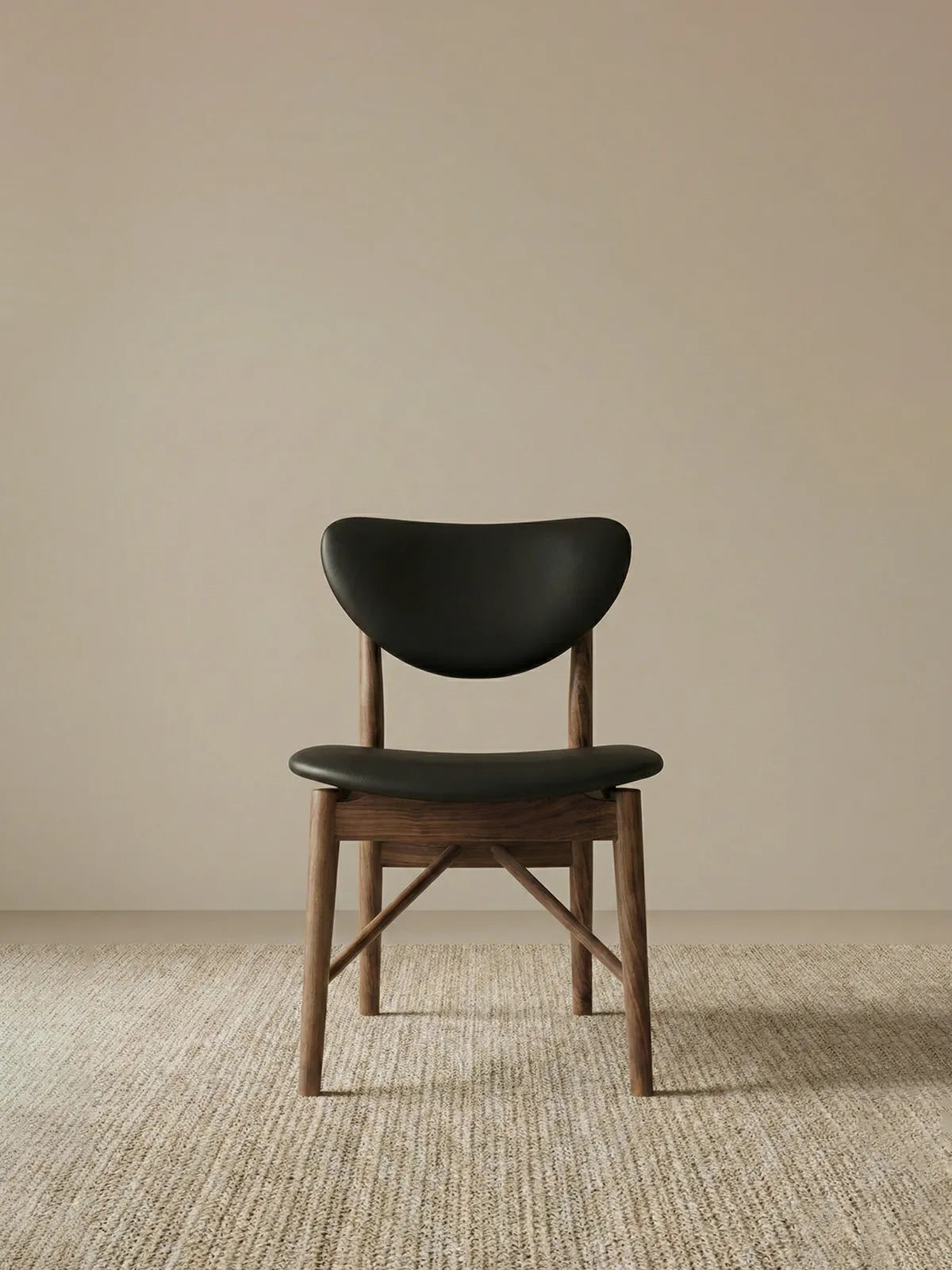 Clean front view of the Sylvan mid century walnut dining chairs, featuring a solid black walnut frame and black leather seat.