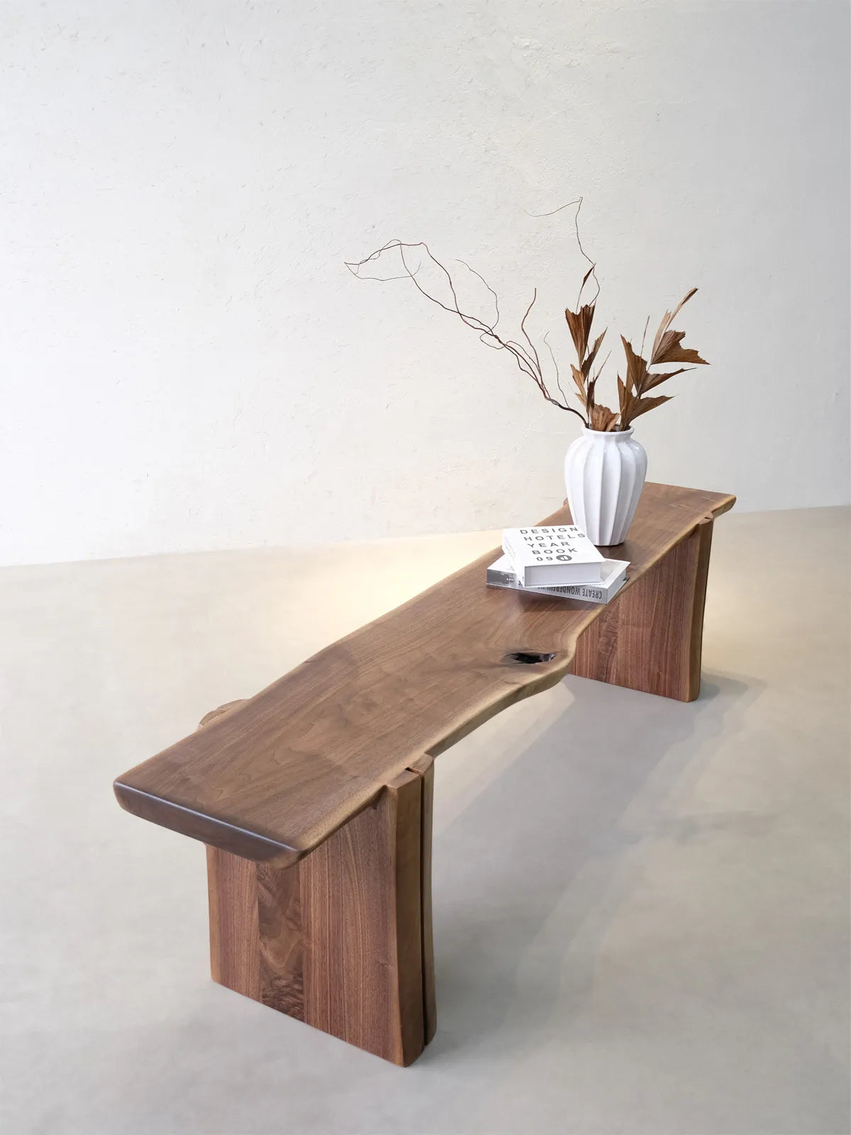 Walnutry Wilder live edge bench styled in a warm interior, showing its natural walnut grain, organic seat edge, and sculptural slab-leg form.