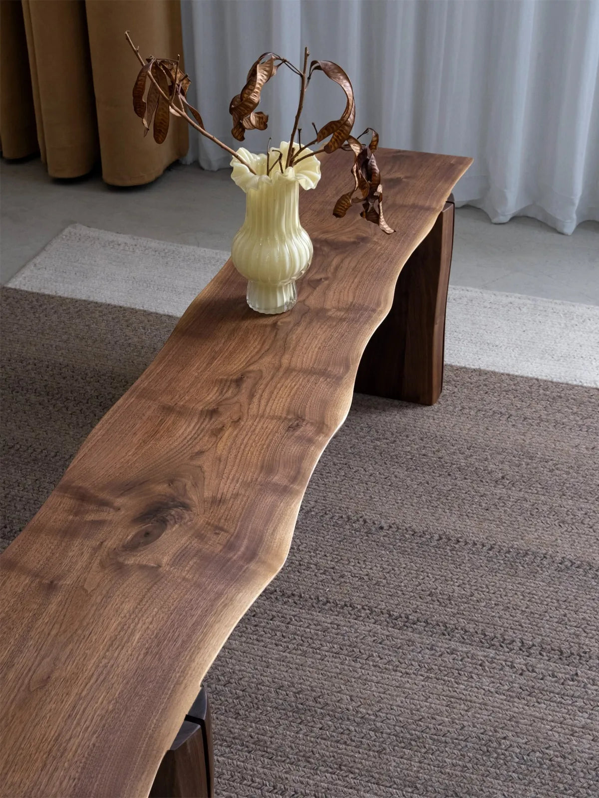 Walnutry Wilder natural edge bench close-up showing organic walnut grain variation, soft transitions, and the unique profile of the live edge seat.