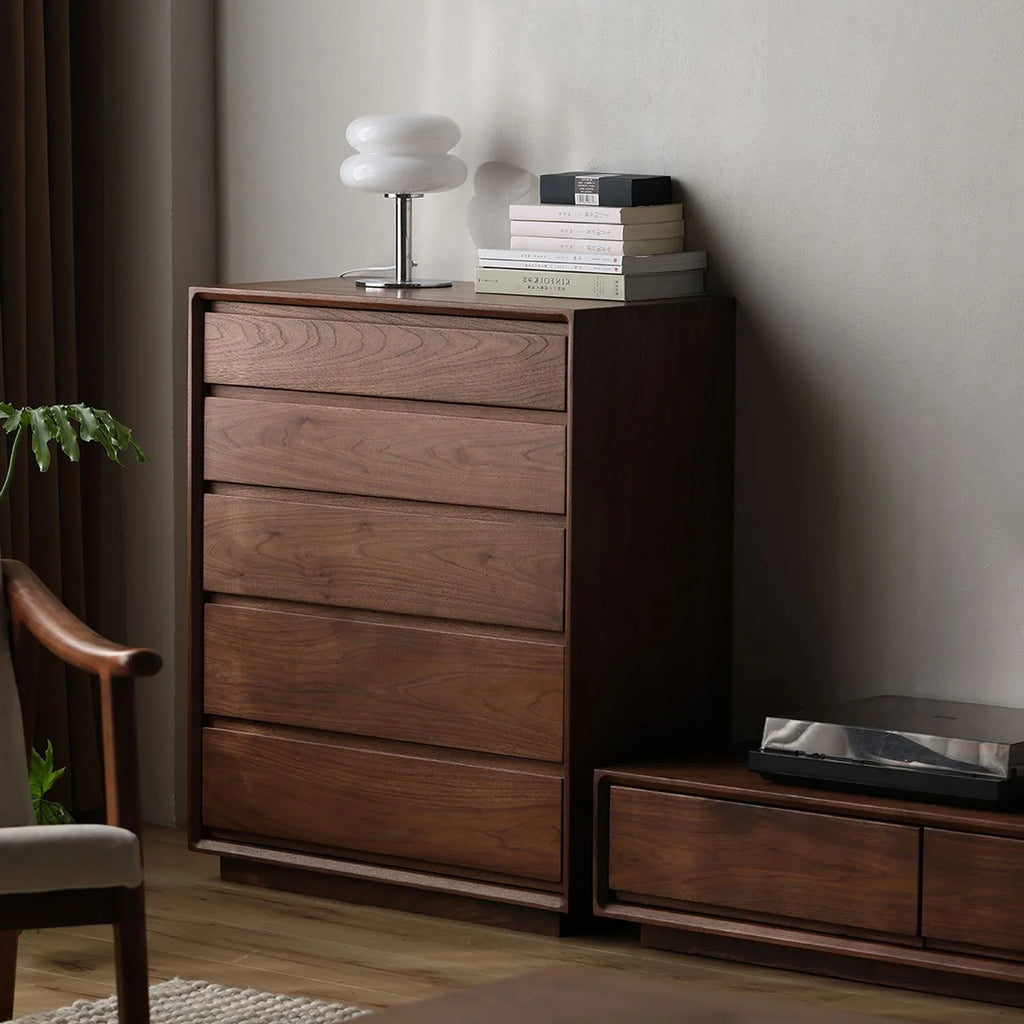 Solid wood bedroom chest of drawers with modern white lamp and stacked books on top