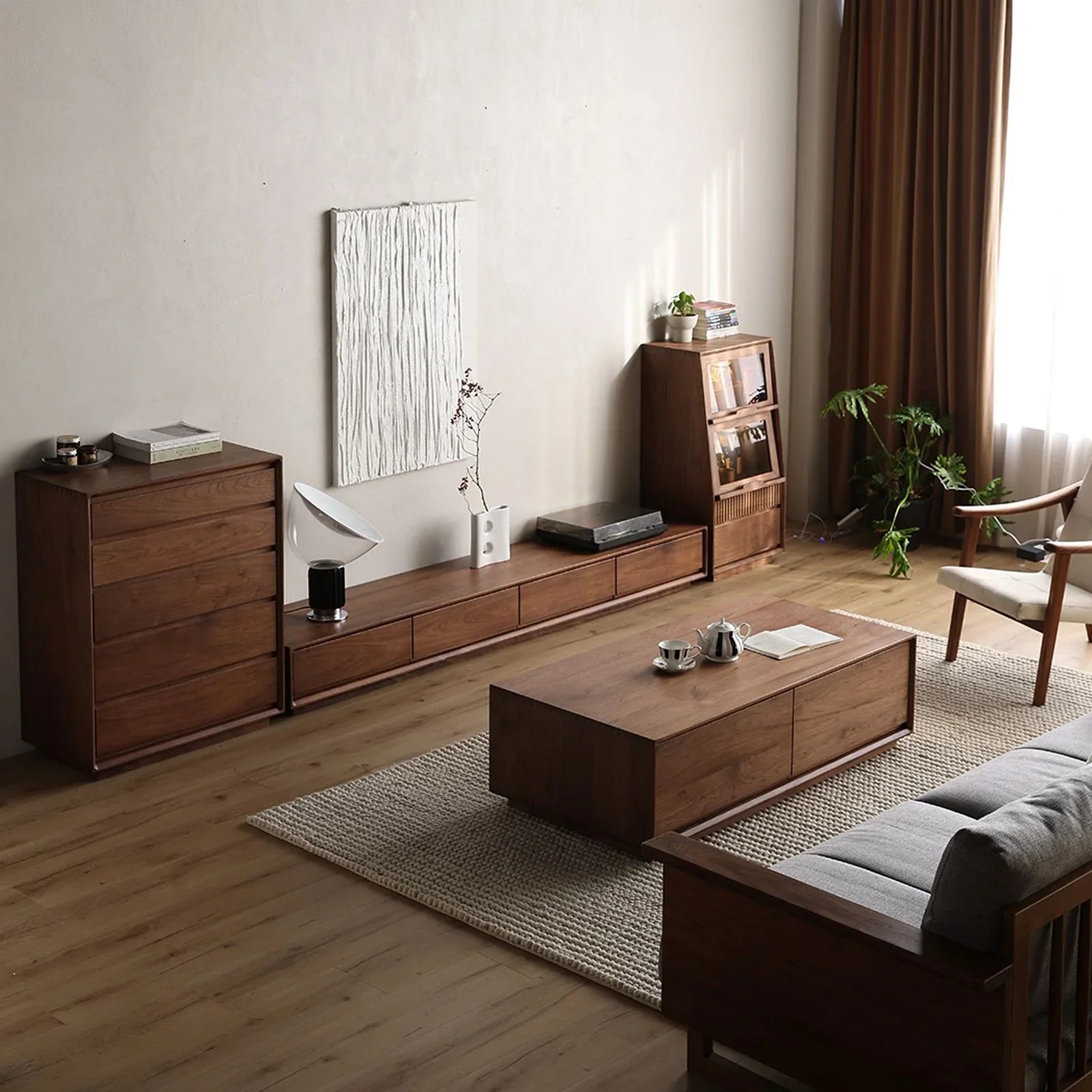 Minimalist living room corner with solid wood walnut chest, low TV cabinet, coffee table, and armchair