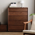 Solid wood bedroom chest of drawers with books and modern white lamp on top, next to wooden armchair