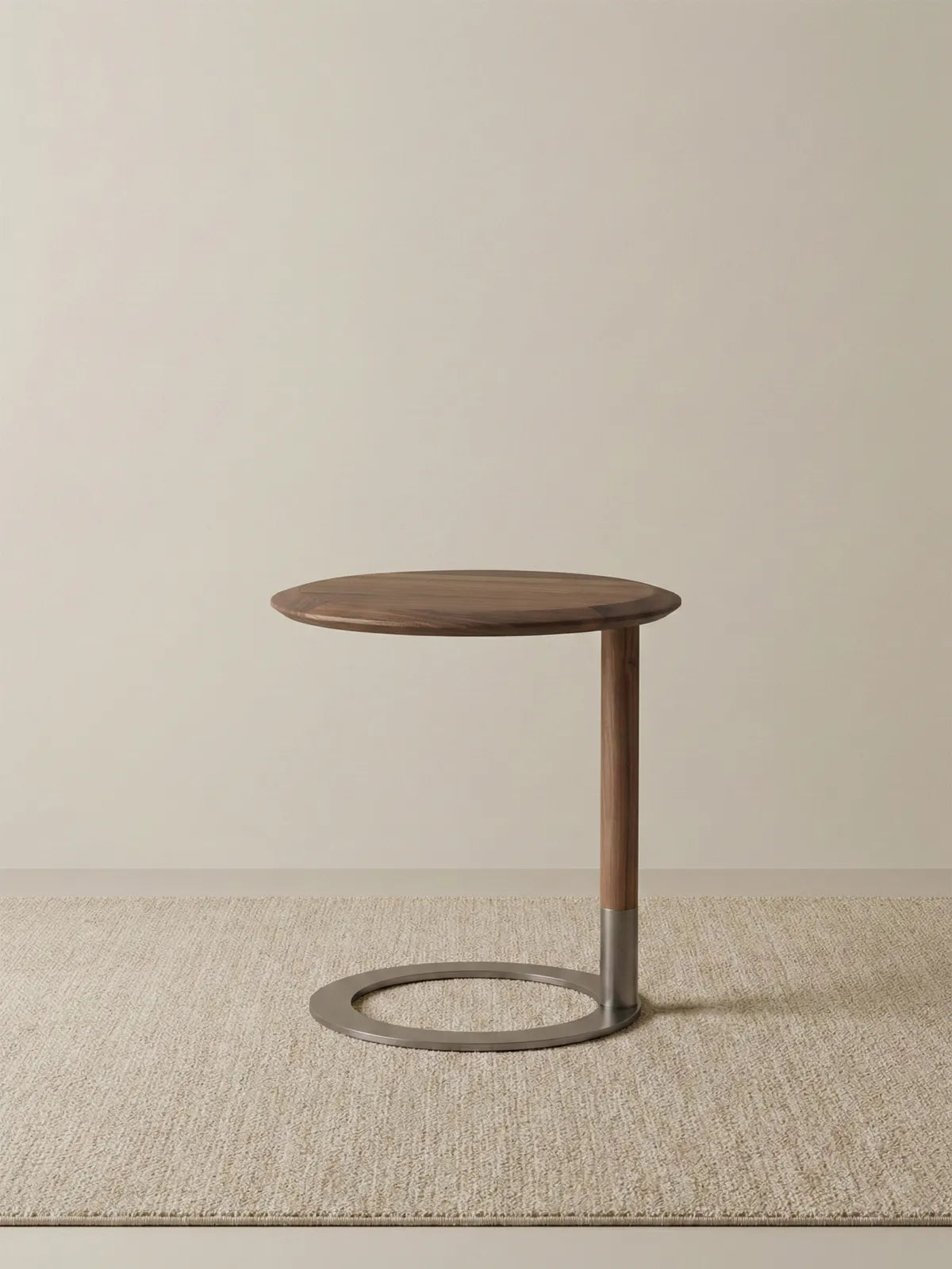 Low angle view of the C-table showing the weighted metal ring base and solid walnut stem on a textured rug.