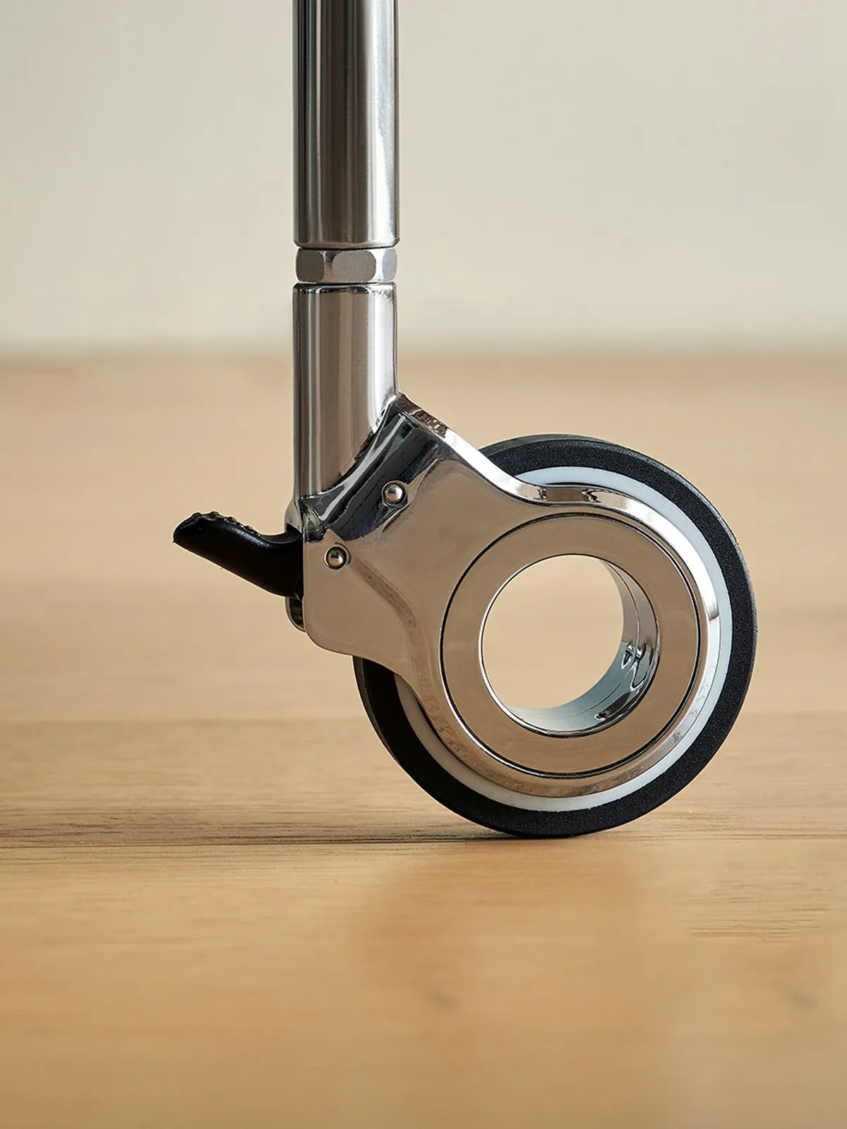 Close-up detail of the heavy-duty chrome caster wheel with non-marking tire on the Kurumi bar cart.
