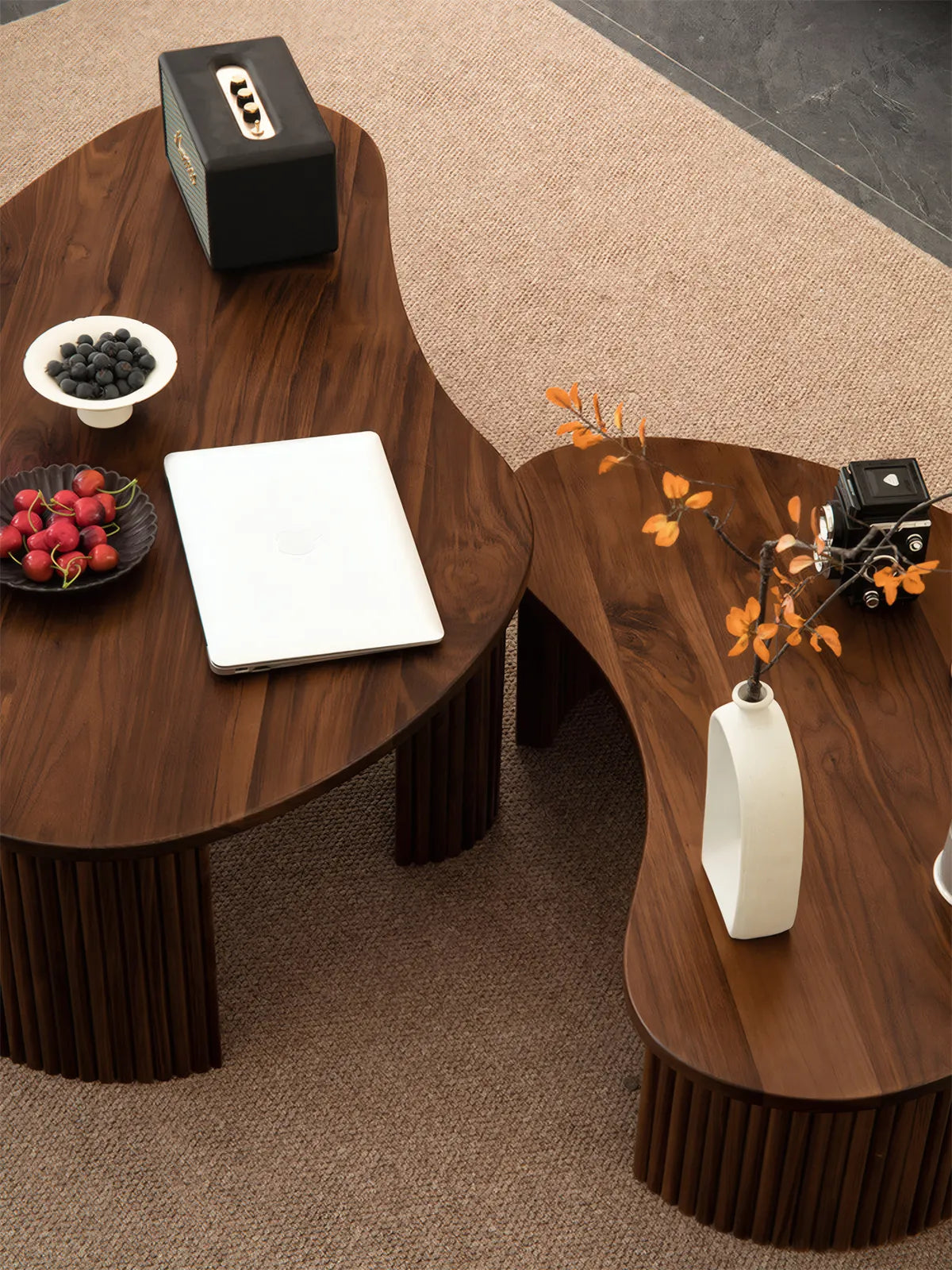 "Kurumi nesting tables separated into two distinct surfaces, styled with fruit bowl and vintage camera."