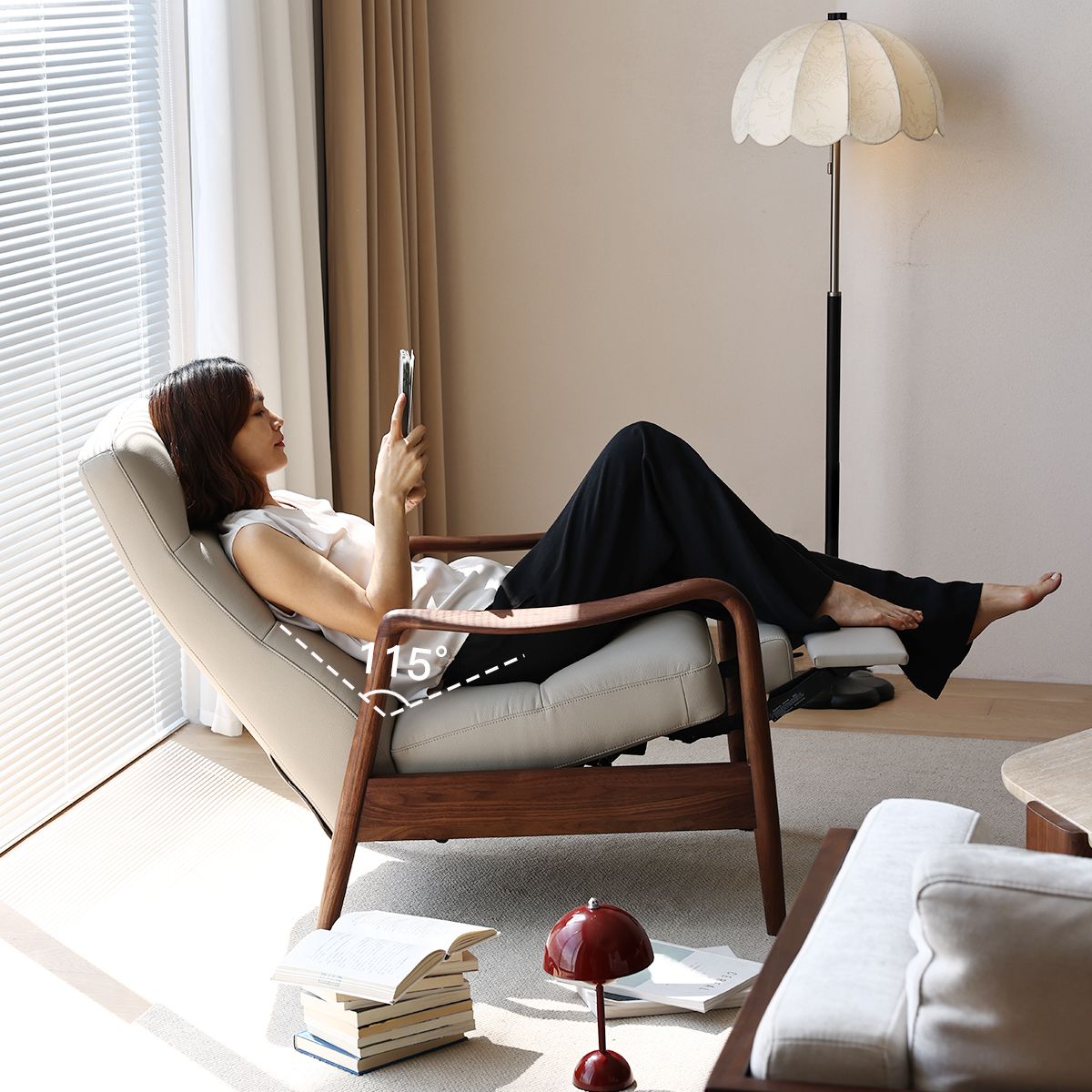Woman reclining on a modern walnut armchair with adjustable footrest in a bright living room