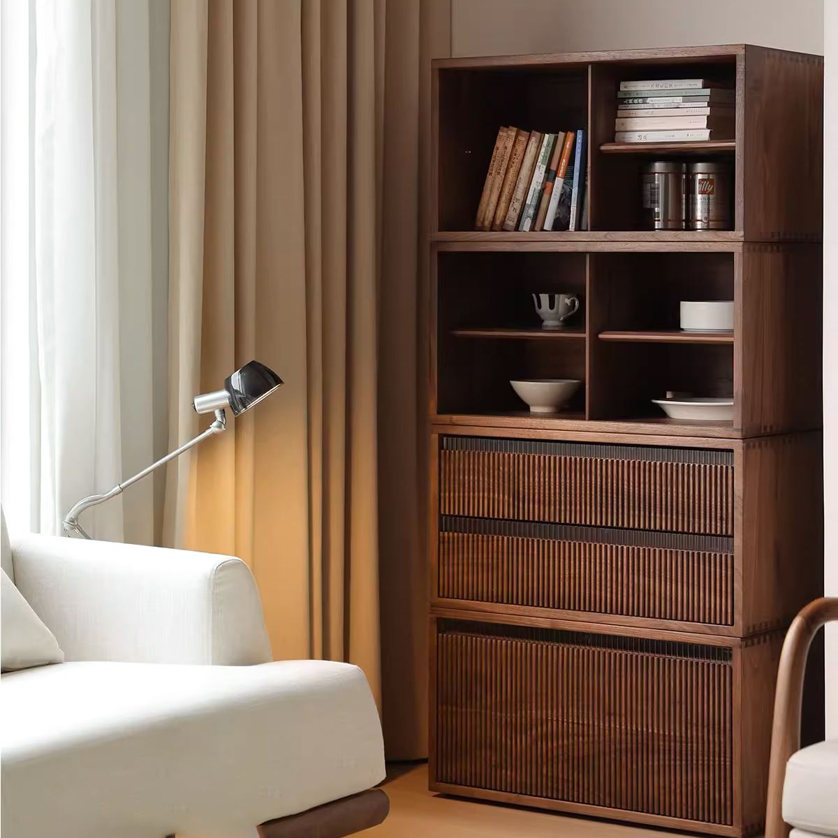 Modern wooden shelving unit with books, cups, and kitchenware beside white sofa and metal lamp