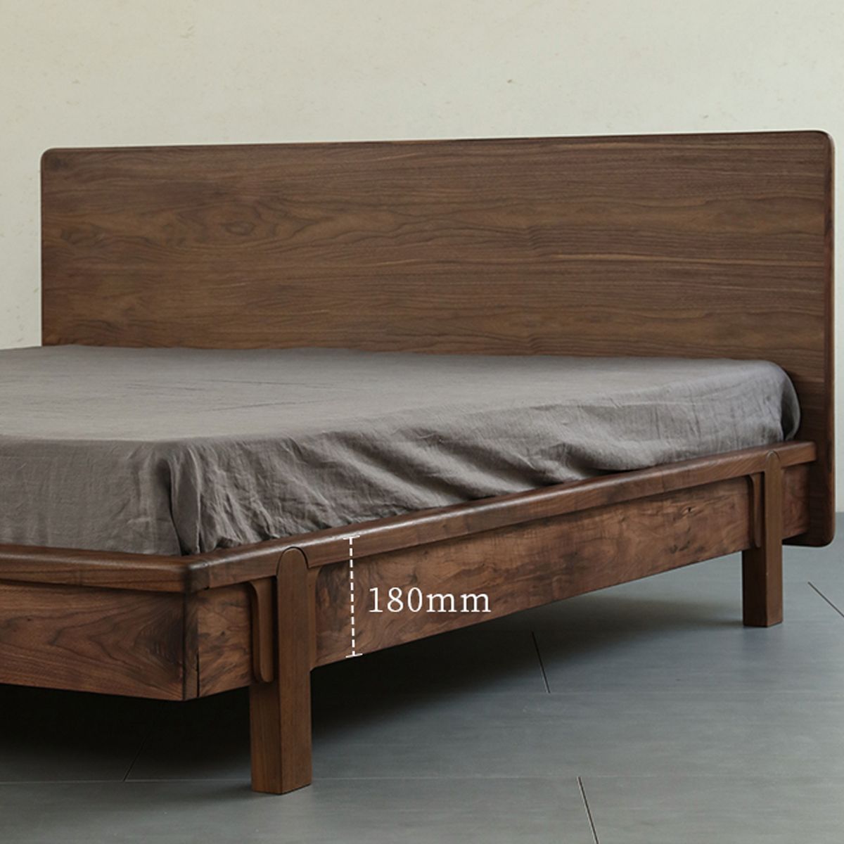 Wooden bed frame with a simple headboard and gray bedding, featuring 180mm clearance under frame