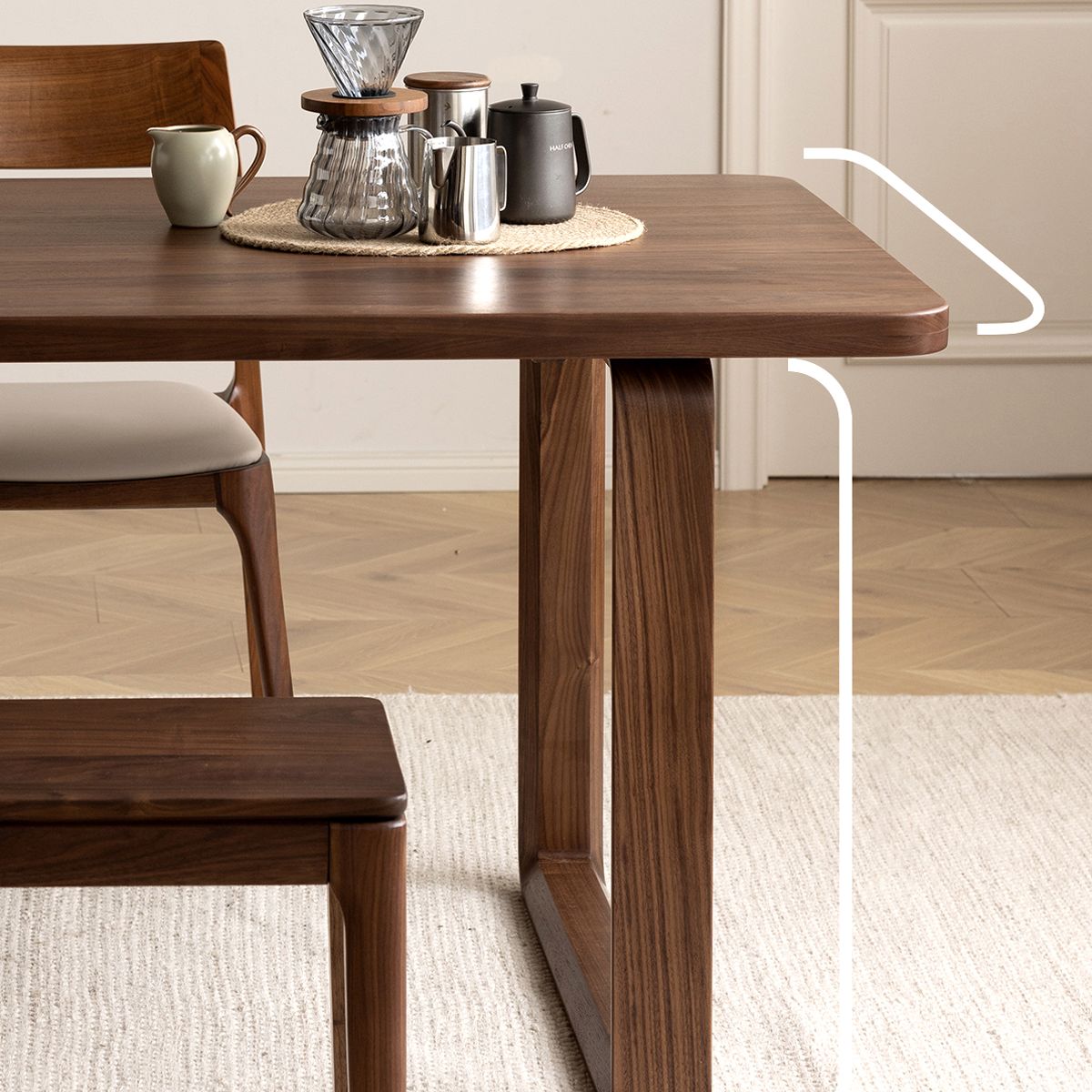 Modern wooden dining table with glass coffee dripper, metal kettle, and cozy chair on beige rug