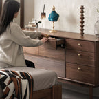 Woman opening drawer of wooden dresser in stylish bedroom with decorative items on top