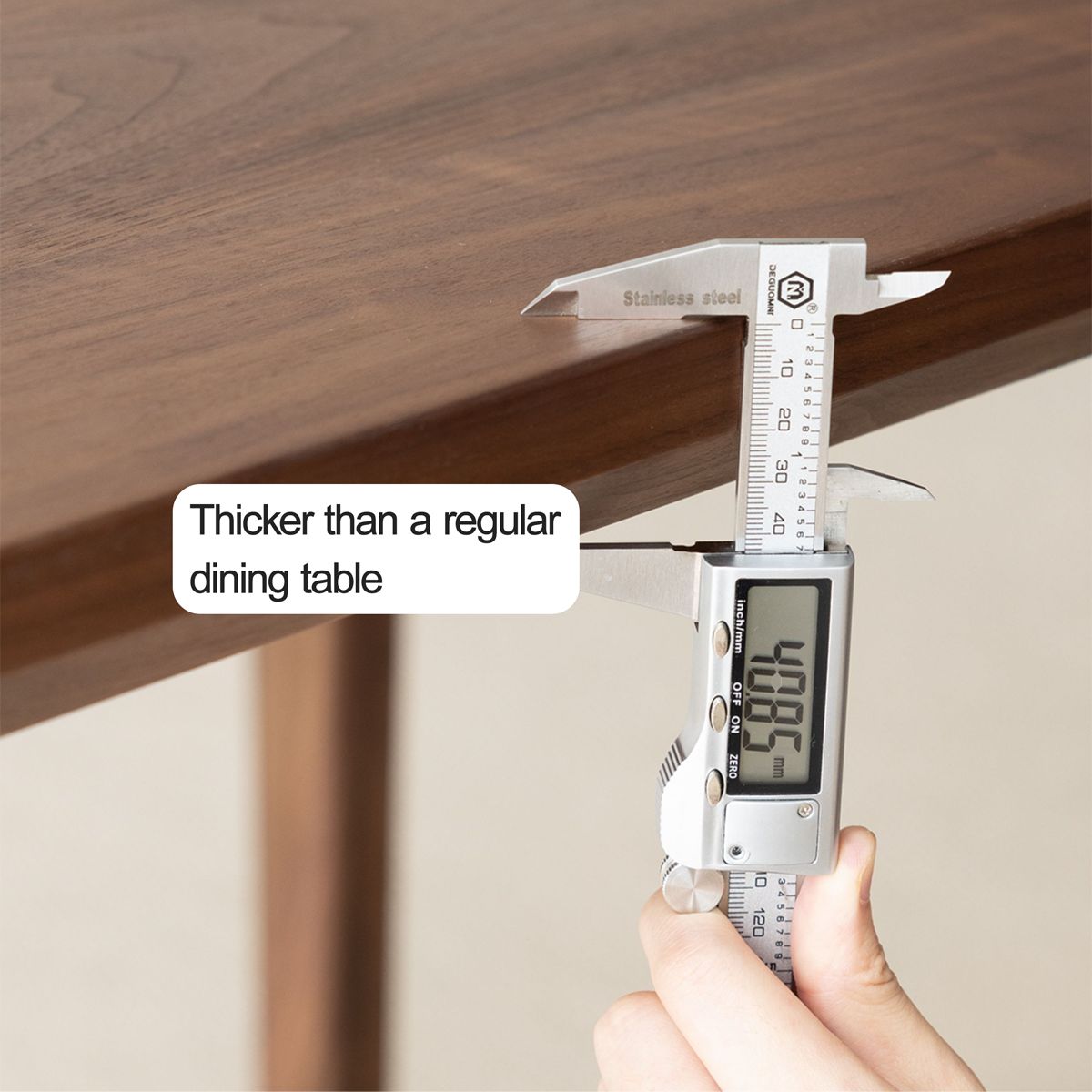 Close-up of digital caliper measuring the thickness of a wooden dining table at 49.97mm