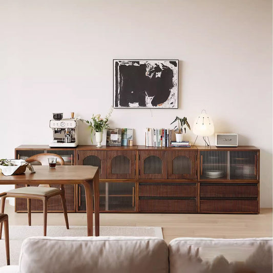 Modern living room with wooden sideboard, espresso machine, books, plants, abstract black-and-white wall art