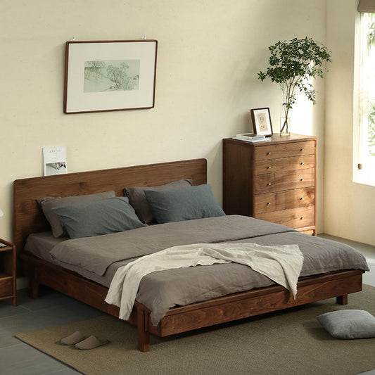 Minimalist bedroom with wooden bed frame, gray bedding, wooden dresser, and potted plant by window