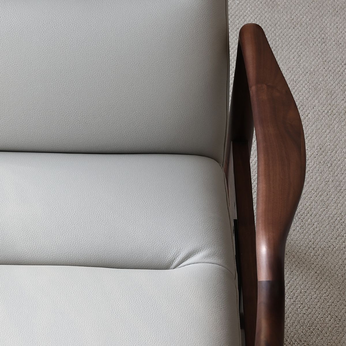 Close-up of beige leather cushion and solid North American black walnut armrest on Walnutry chair