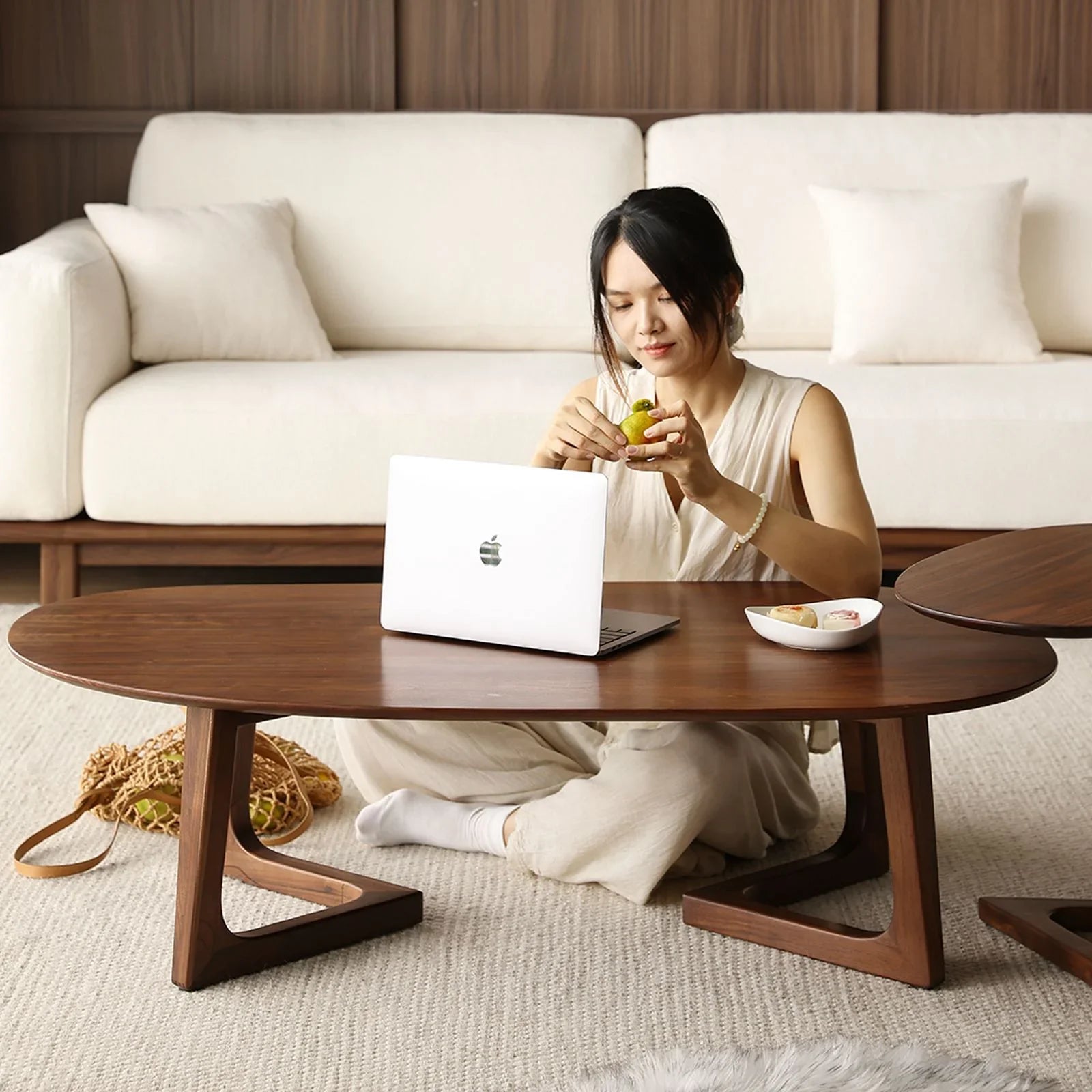 Woman sitting on carpet using laptop at solid black walnut coffee table in modern living room