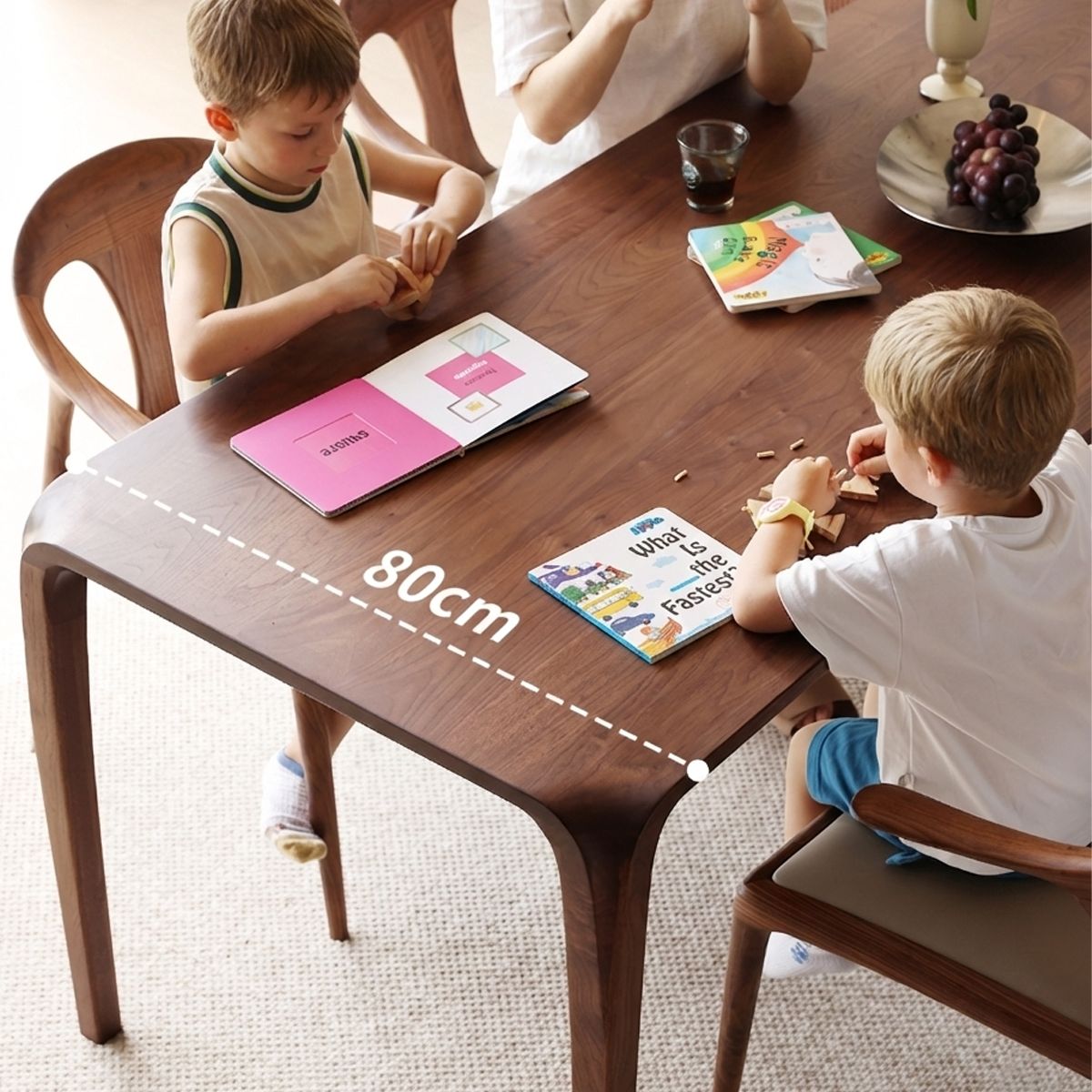 Two young boys sitting at 80cm wooden table playing with toys and reading books in bright room