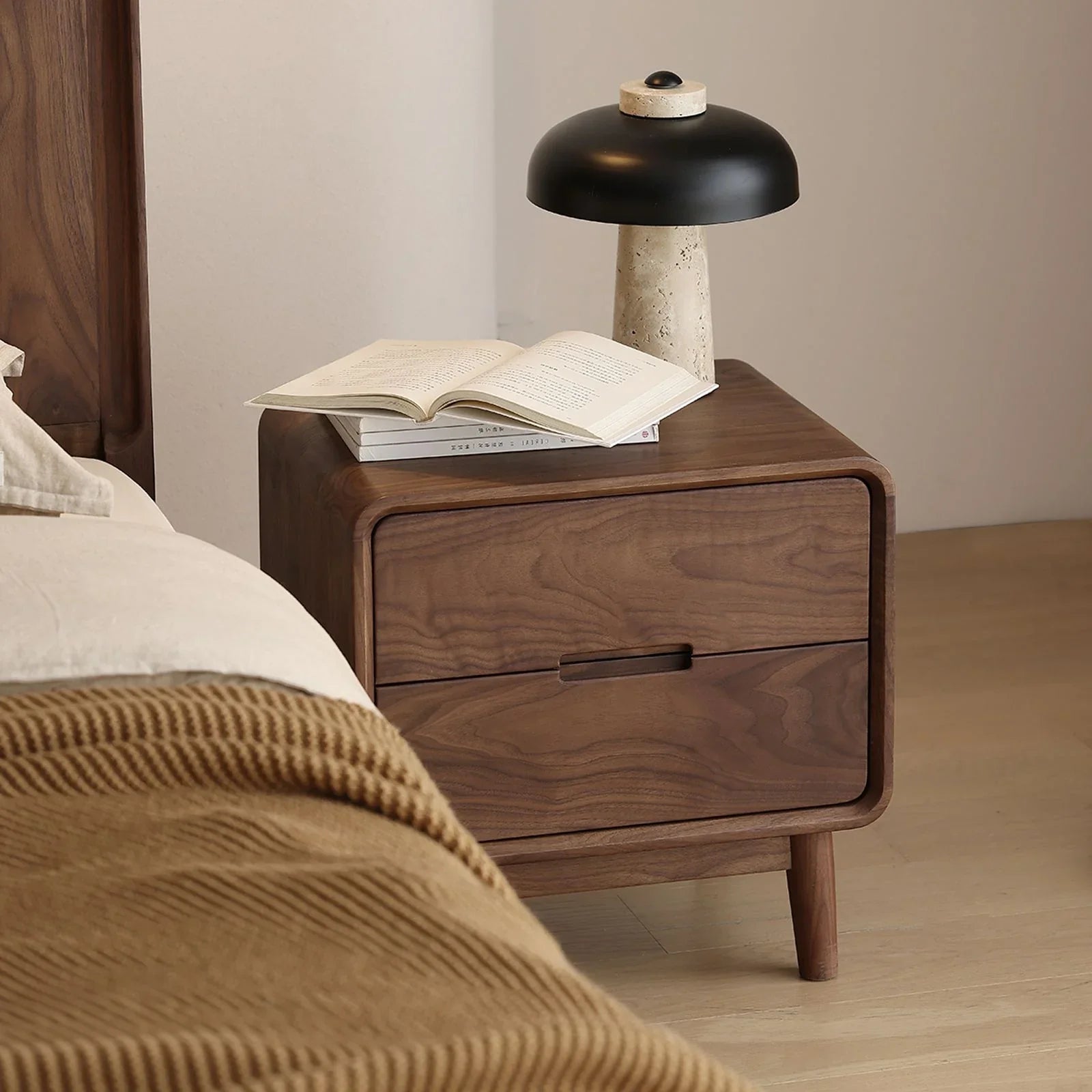 Solid walnut nightstand with two drawers, modern black and stone table lamp, and open book in cozy bedroom