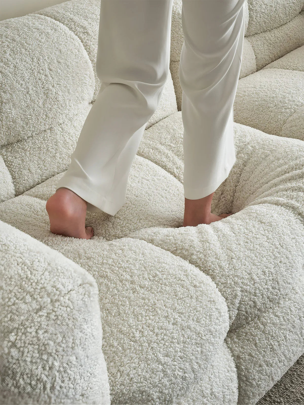 Close up of person walking on soft tufted cushions of the Cumberland modular sofa, demonstrating high-resilience foam and down comfort.