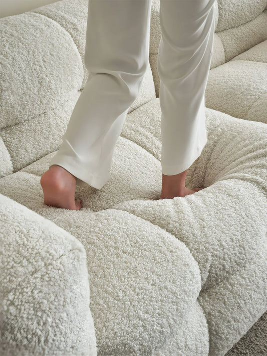 Close up of person walking on soft tufted cushions of the Cumberland modular sofa, demonstrating high-resilience foam and down comfort.