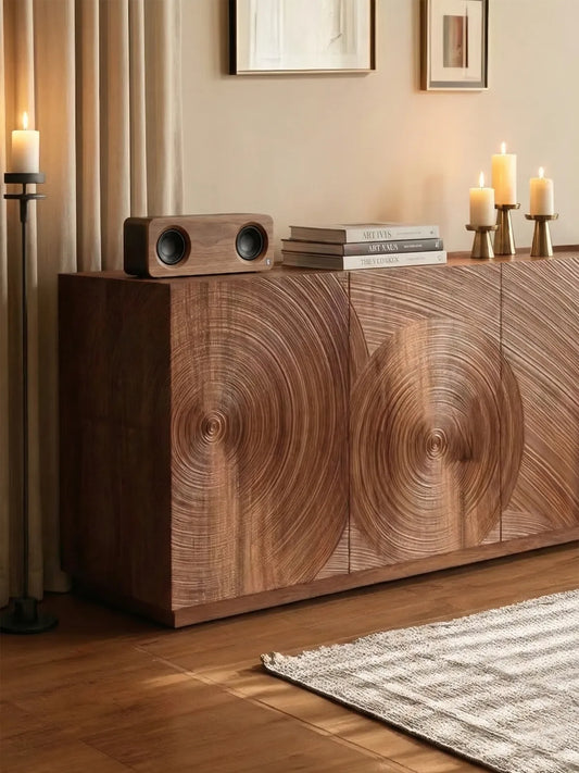 Styled tabletop of the Curator sideboard featuring a wooden speaker, stacked art books, and brass candle holders.