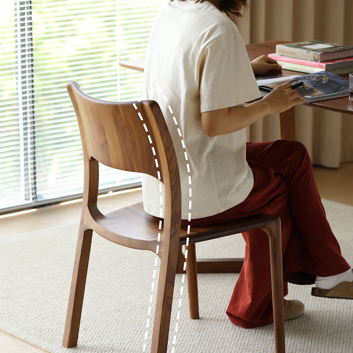 Curved back wooden chair side profile with person sitting reading indoors near window